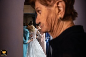 In Fossombrone, a soft focus captures the grandmother in the foreground as the bride receives help with her dress behind.